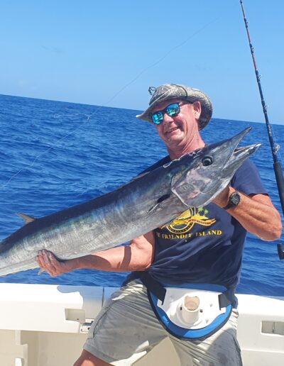 Happy angler holding a large fish on a boat in the ocean.
